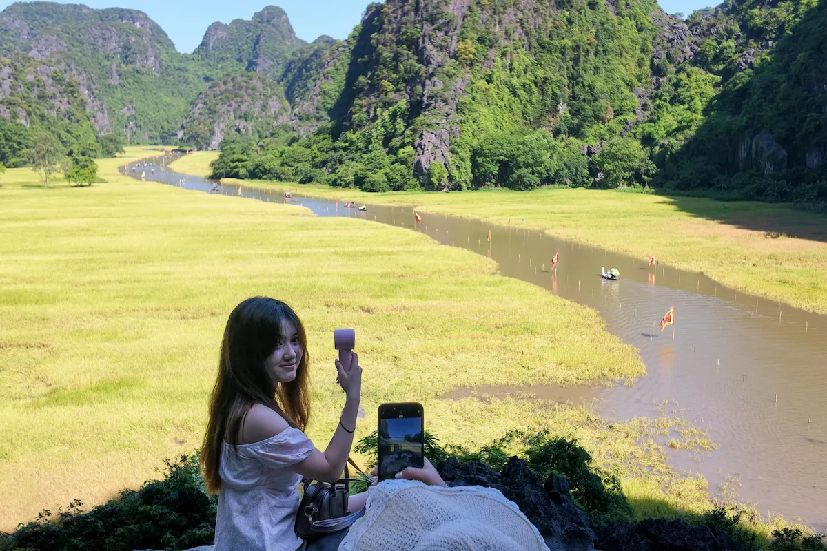 Tourist taking photos during the best time for Tam Coc boat tour in harvest season