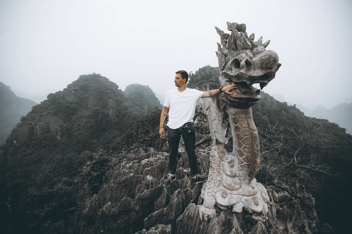 Traveler standing beside the dragon statue at Mua Cave Dragon Peak in Ninh Binh