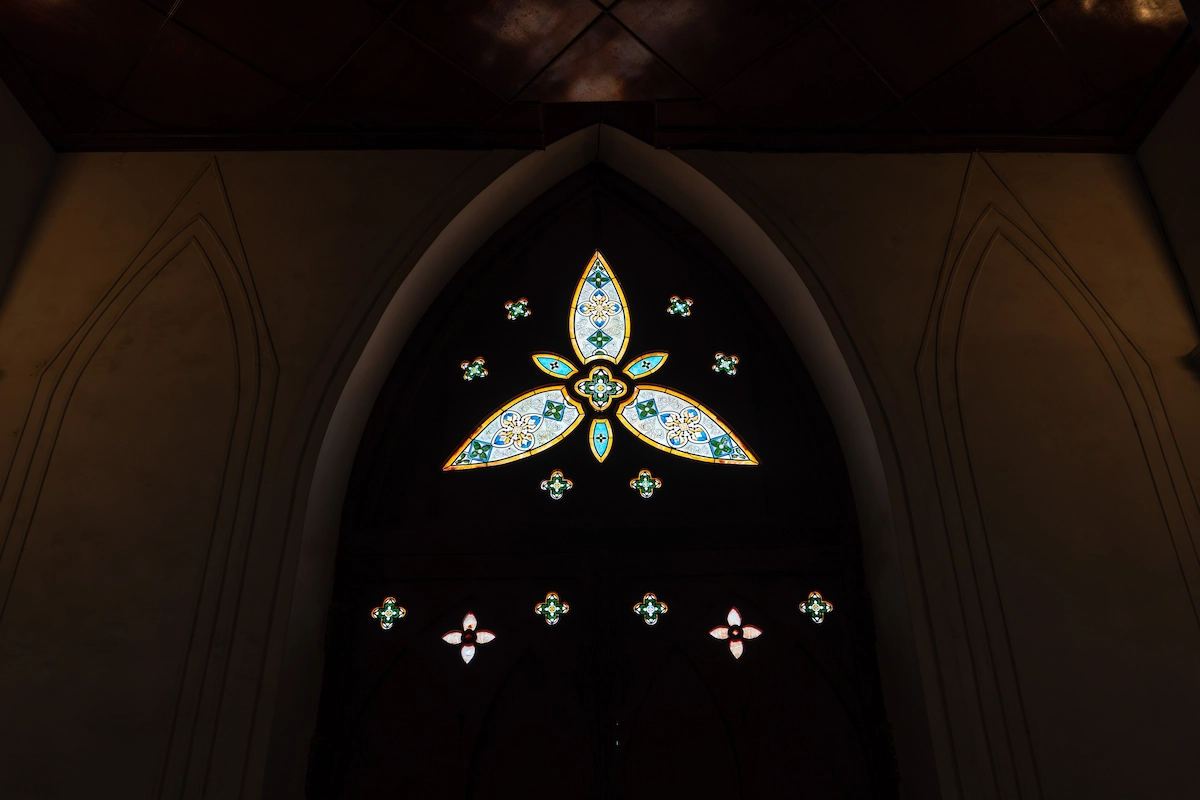 Stained glass window inside So Kien Basilica, depicting intricate floral and religious motifs