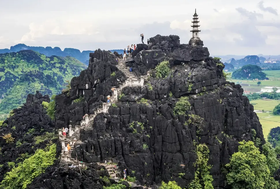 Mua Cave hiking guide featuring hikers on the steep rocky trail to the viewpoint