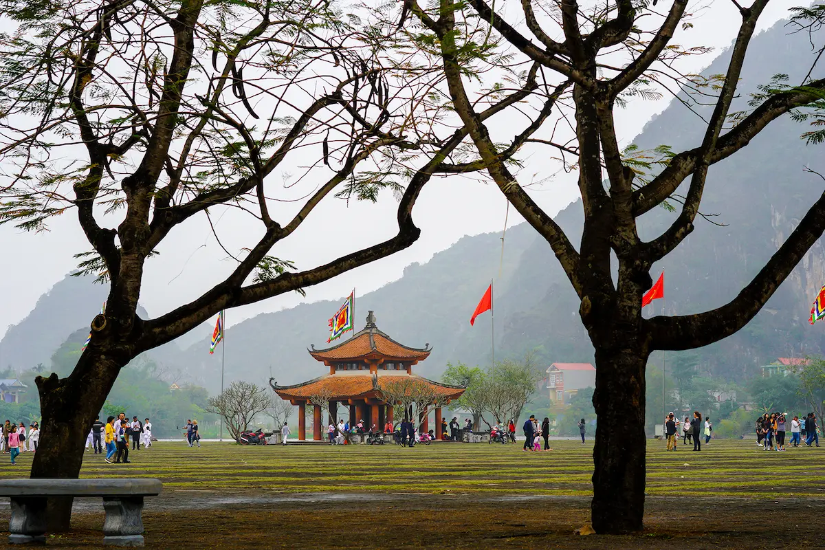 Traditional Vietnamese temple surrounded by trees and limestone mountains in Ninh Binh
