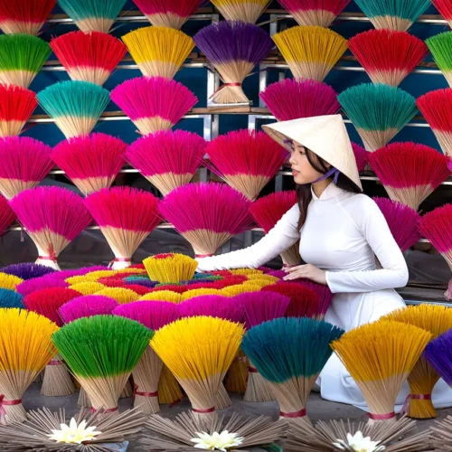 Woman in ao dai among colorful incense bundles at Quang Phu Cau Village