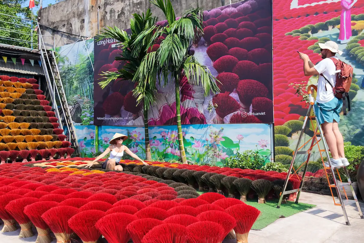 Visitors photographing red incense bundles at Quang Phu Cau incense village