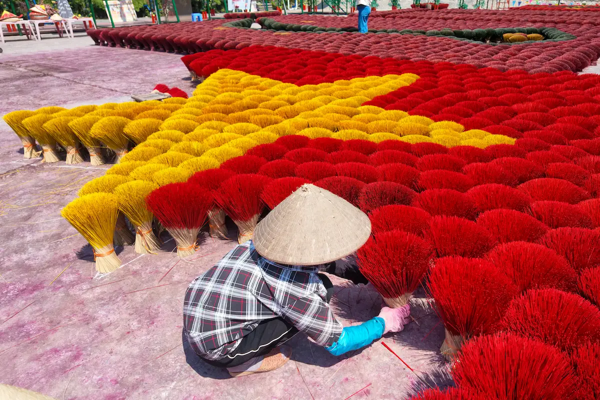 Local artisan arranging red incense bundles at Quang Phu Cau village