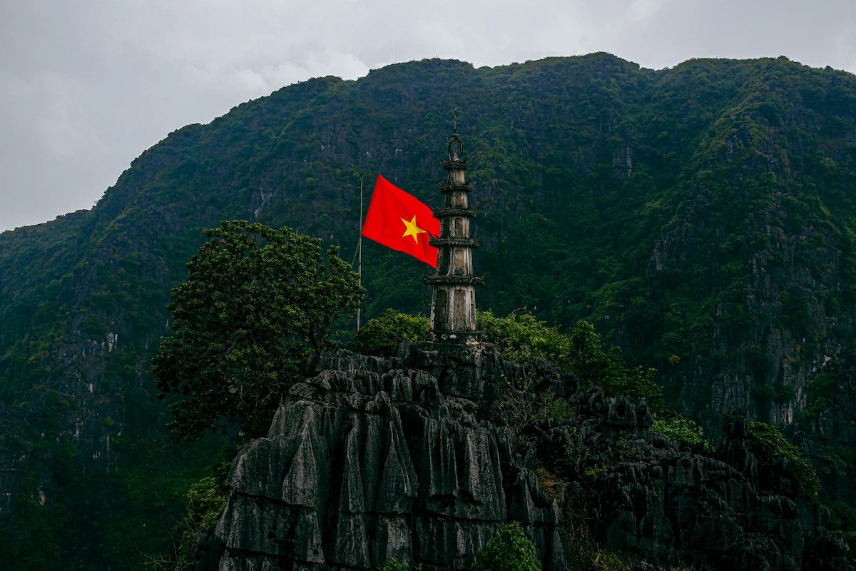Mua Cave pagoda and Vietnamese flag surrounded by limestone mountains in Ninh Binh