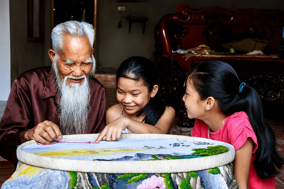 Elderly artisan teaching children traditional embroidery in Van Lam Village