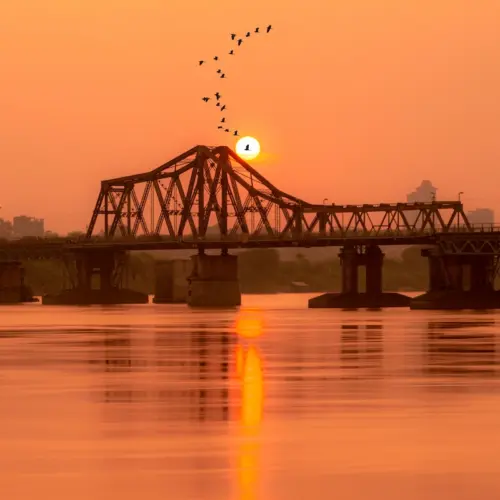 Scenic sunset view over the historic Long Bien Bridge spanning the Red River on a Hanoi culture tour