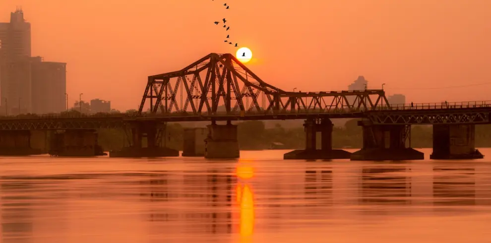 Scenic sunset view over the historic Long Bien Bridge spanning the Red River on a Hanoi culture tour
