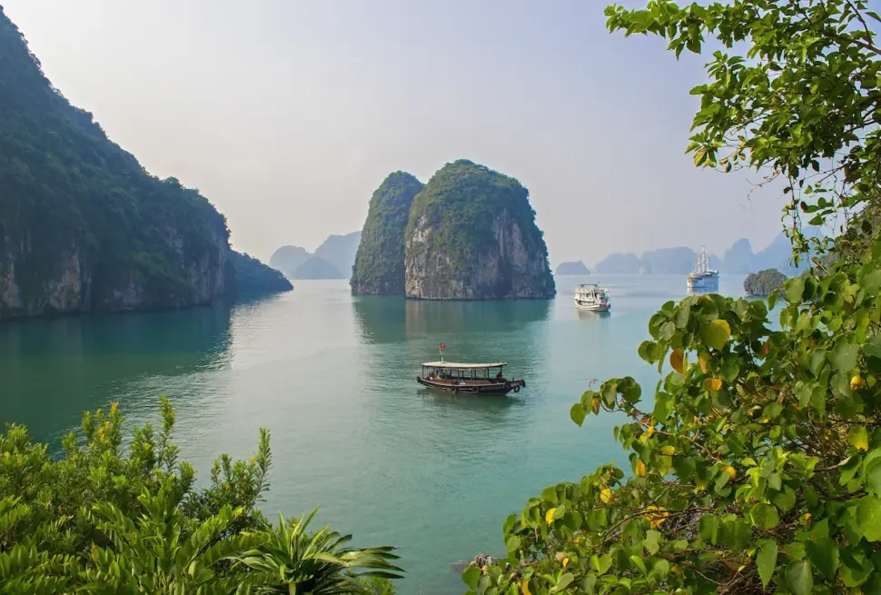 Traditional boats cruise among limestone islands in Ha Long Bay