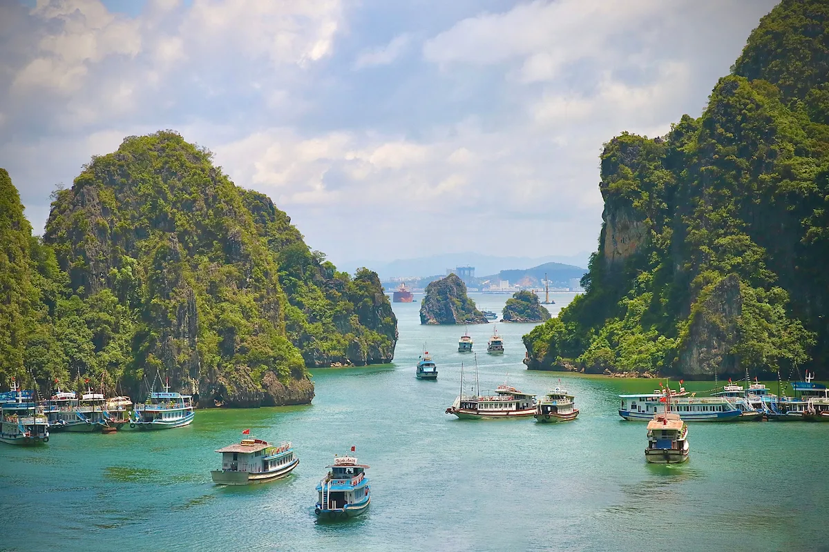 Tourist boats travel through a channel framed by limestone karsts