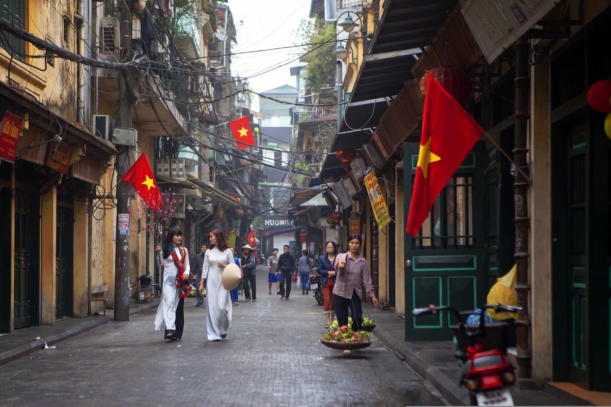 A lively Hanoi Old Quarter street decorated with Vietnamese flags